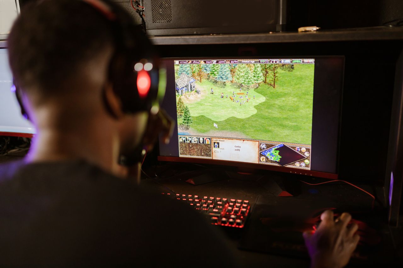 hero-img-01 A gamer intensely playing a strategy game on a high-resolution monitor indoors.